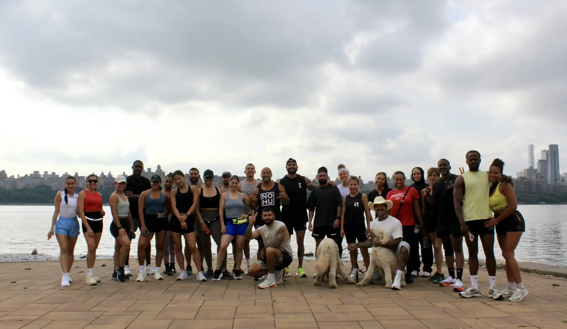 The HudHaus x Reign Running 5K group at the Hudson River waterfront overlooking the New York City skyline