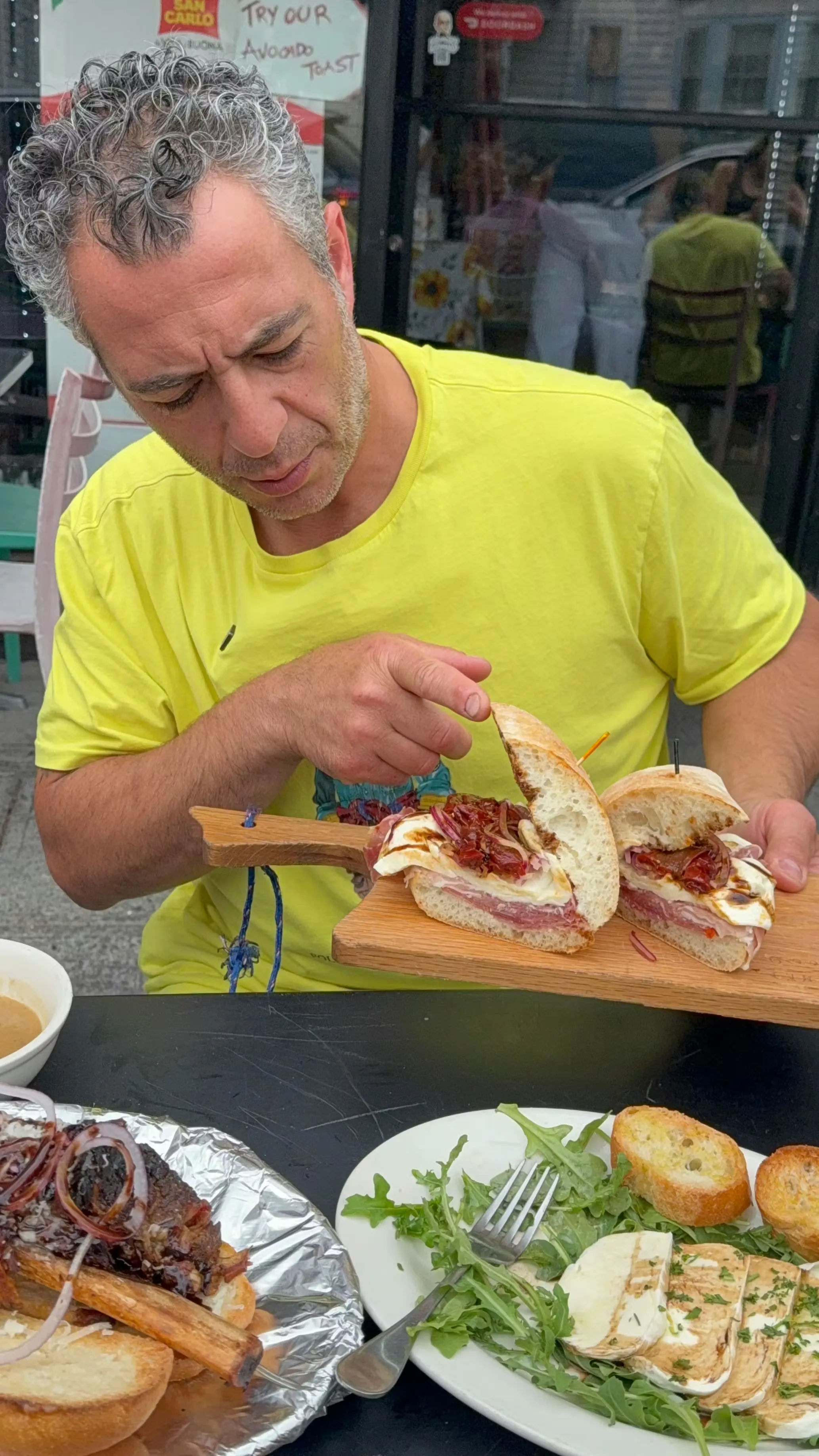 A diner taking the first bite of a Cuomo & Sons sandwich, before-and-after style